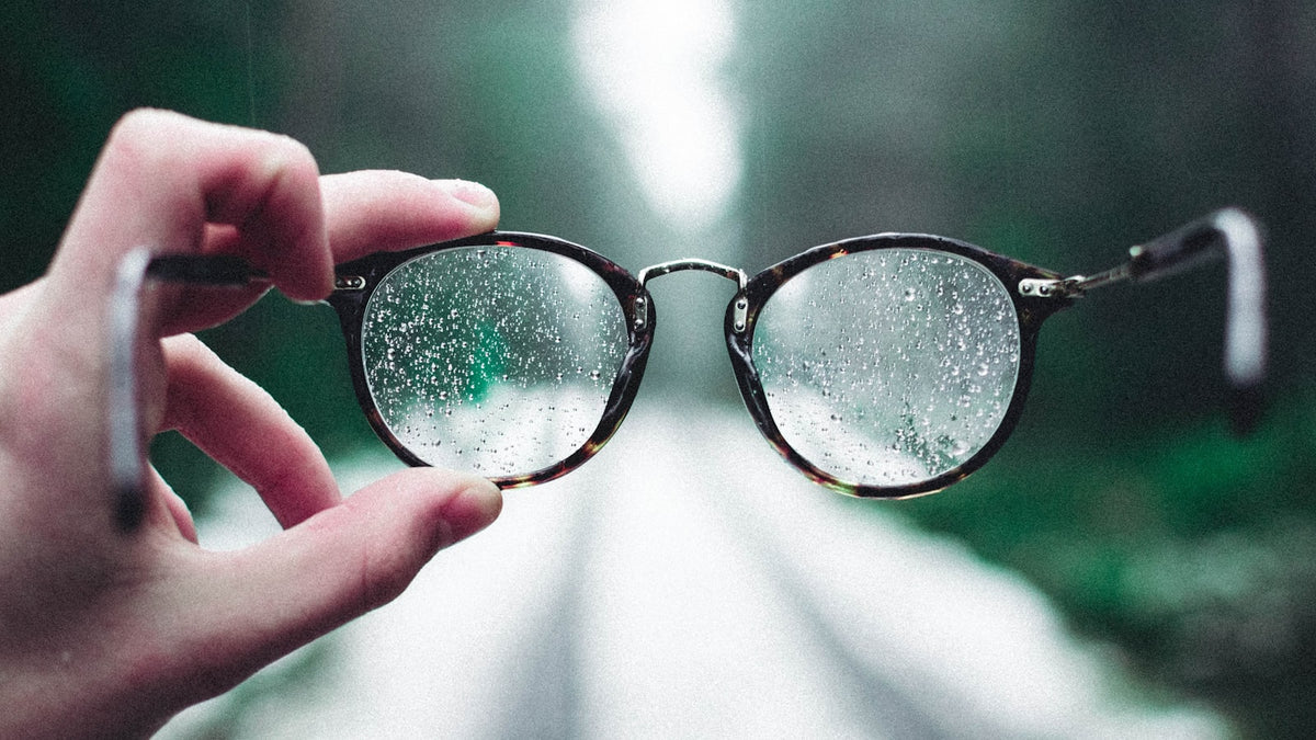 Eyeglasses held up with water droplets on the lenses