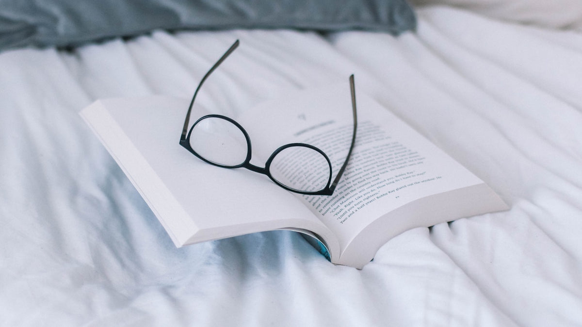 Black-framed reading glasses resting on an open book