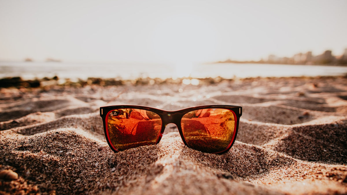 Sunglasses resting on sand in bright sunlight