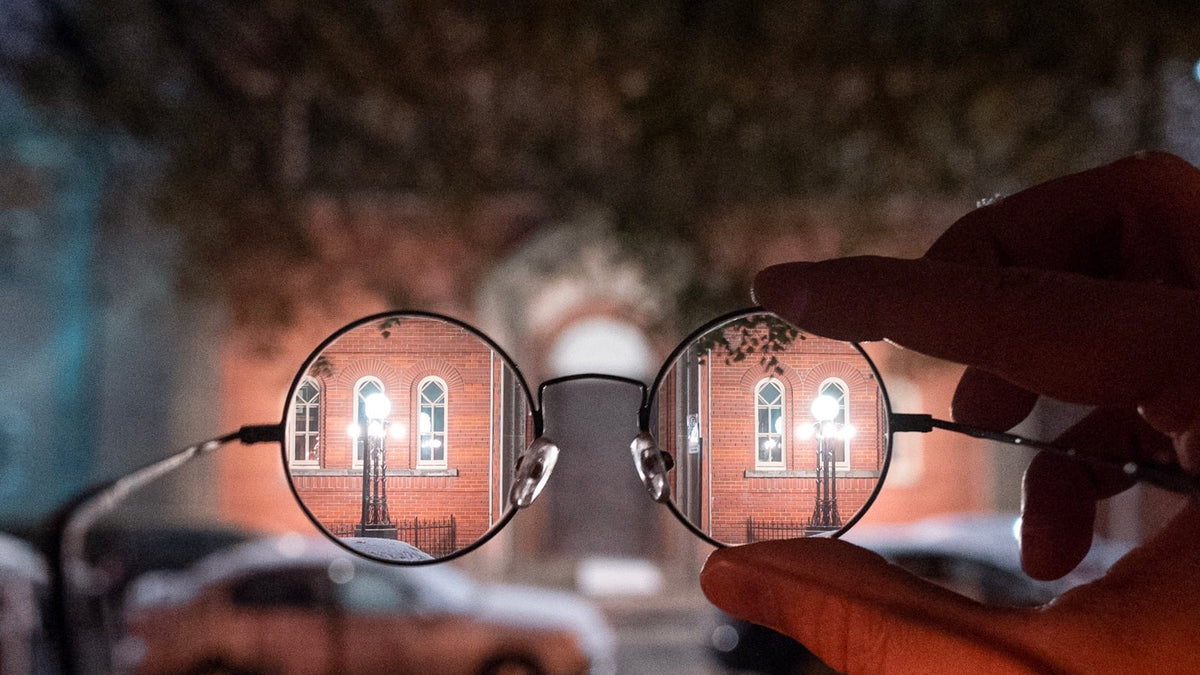 Person holding a pair of black-framed eyeglasses