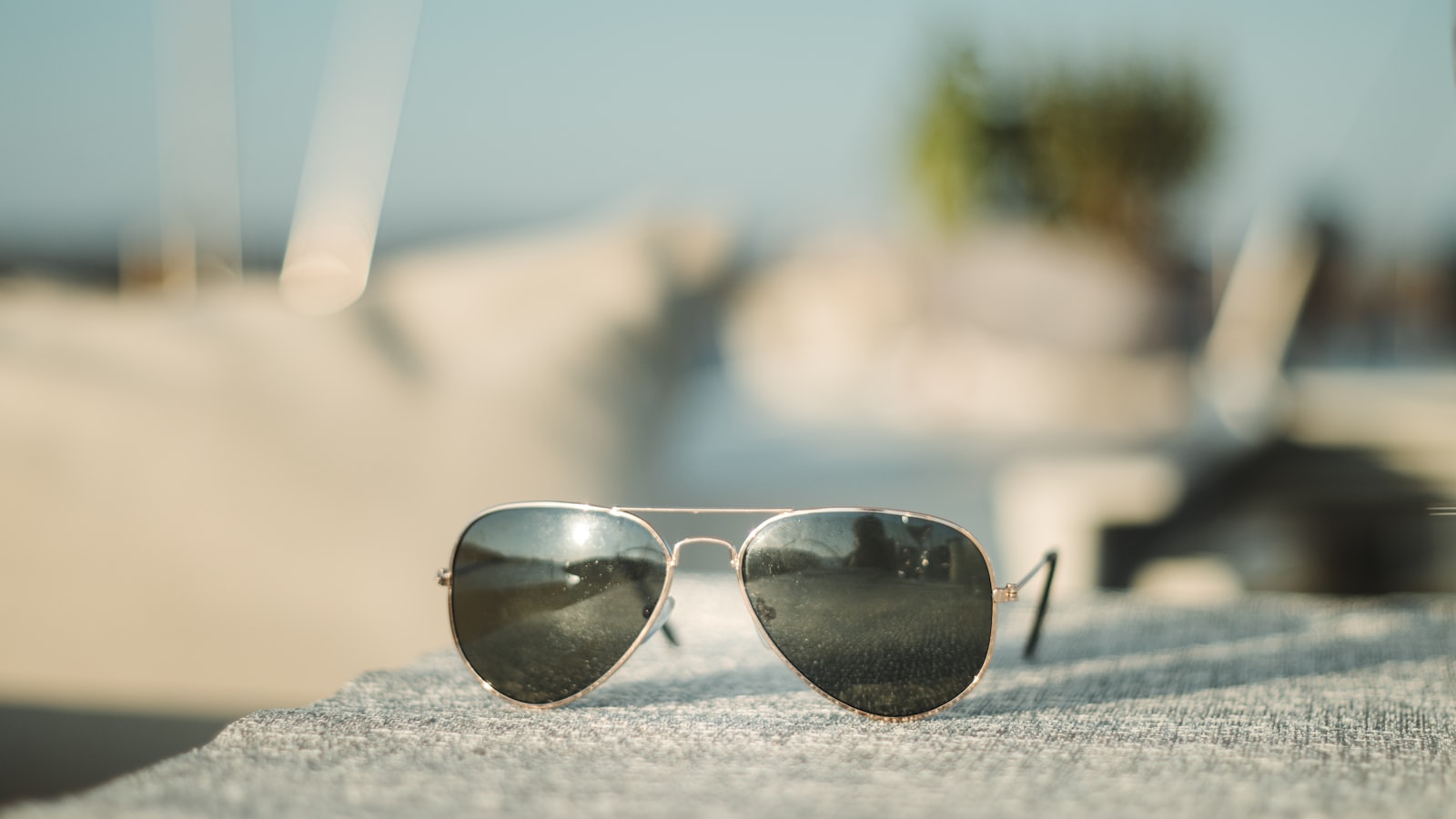 Metal double-bridge aviator sunglasses resting on a sunlit ledge