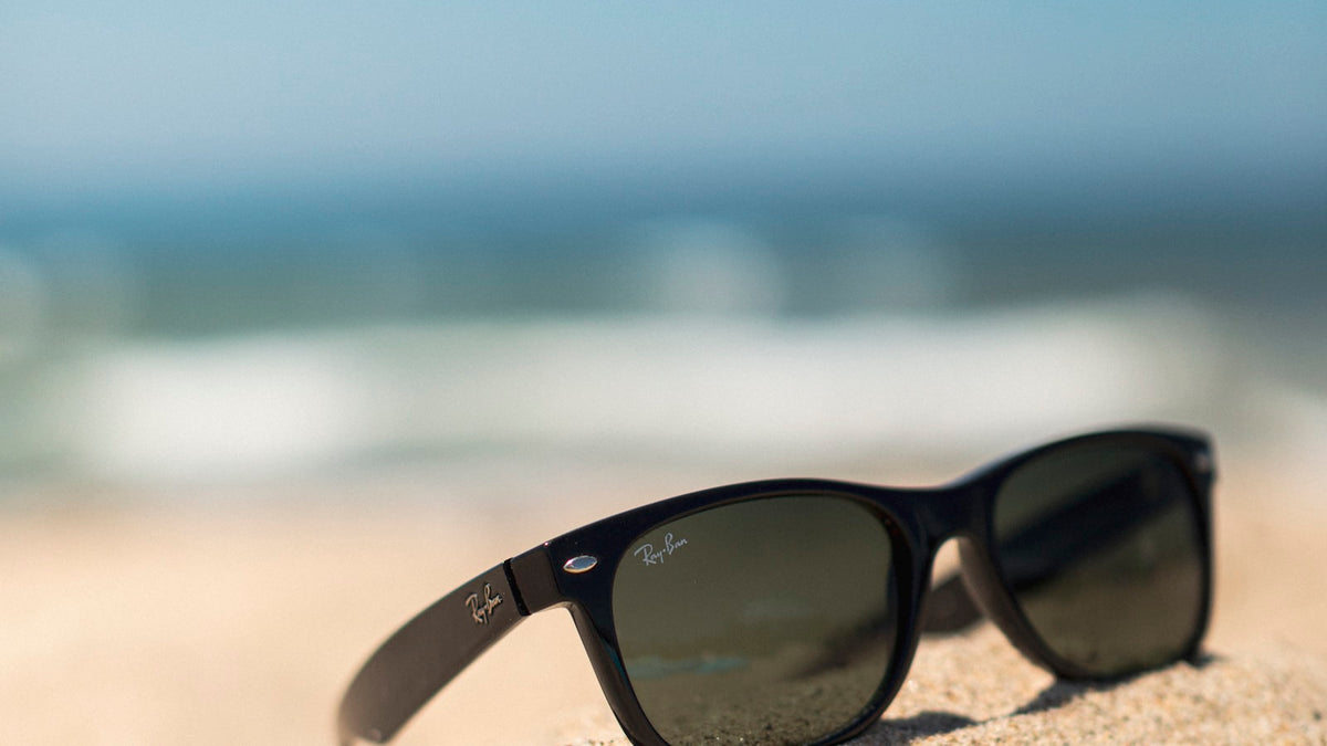 Black sunglasses resting on bright sunlit beach sand