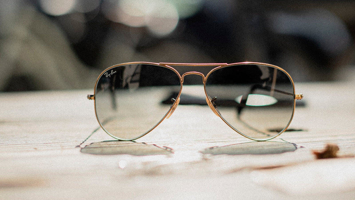 Gold-framed aviator sunglasses on a plain surface