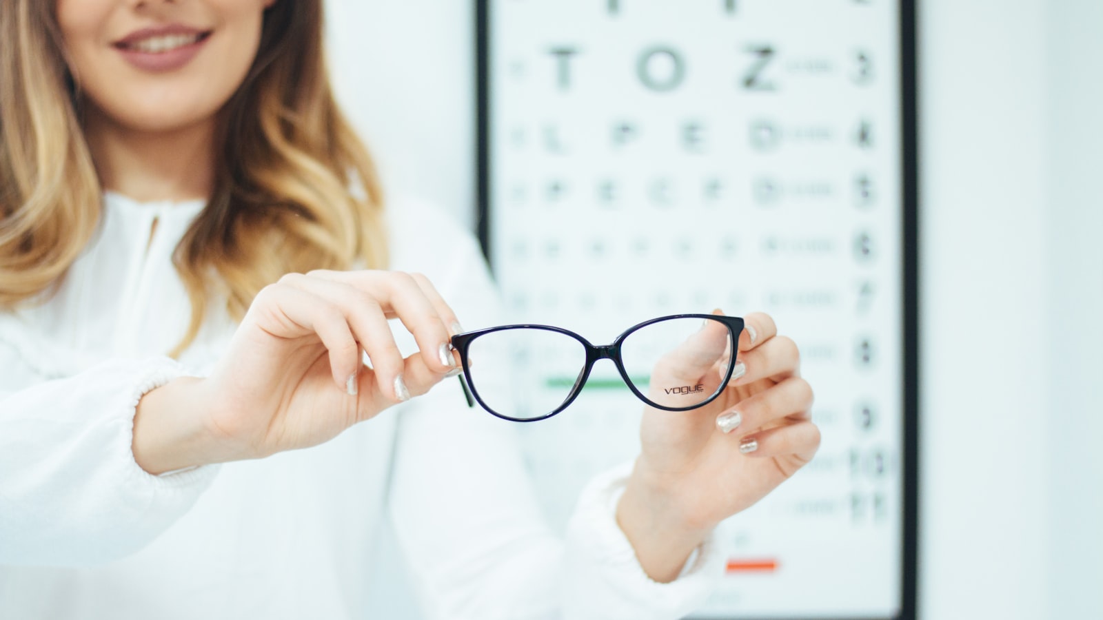 Person holding a pair of glasses by the temples — how to stop glasses sliding down your nose