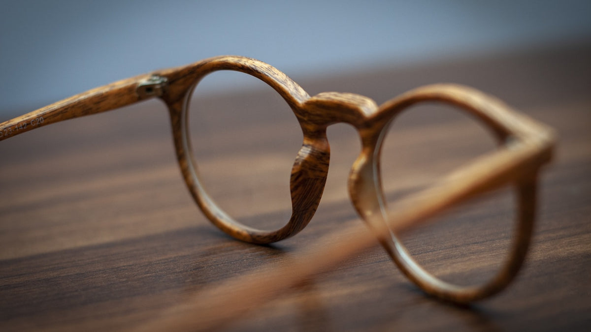Gold metal eyeglasses showing the nose pads on a wooden table