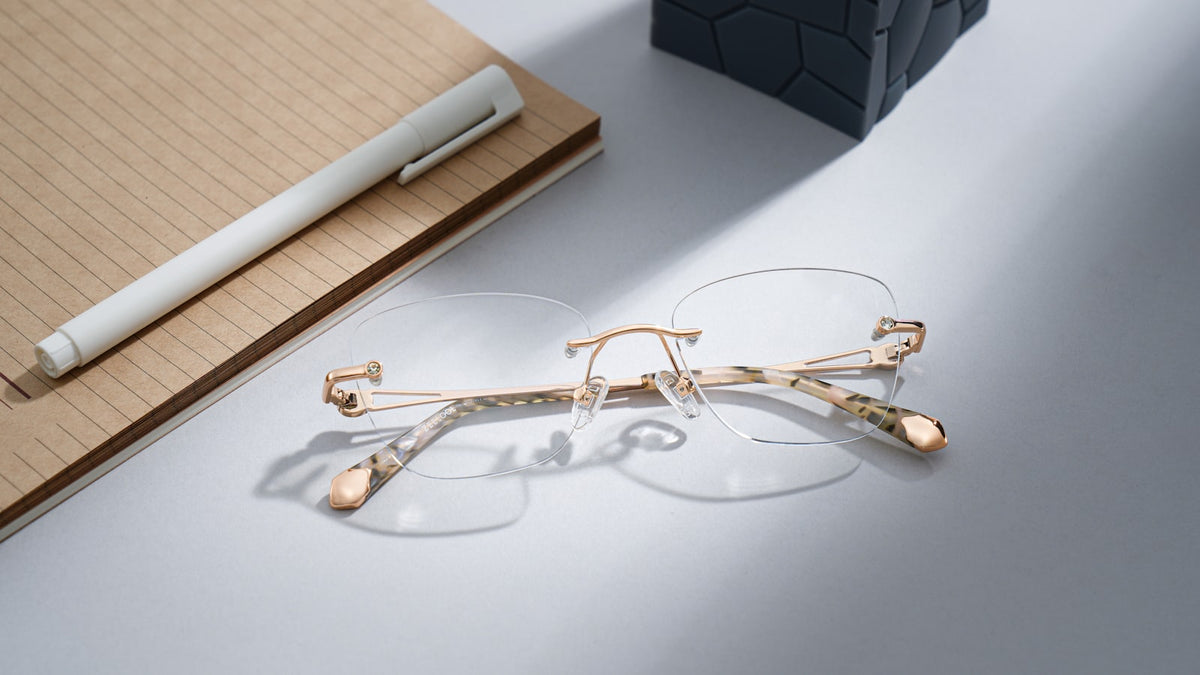 Rimless eyeglasses resting on a notebook with a pen