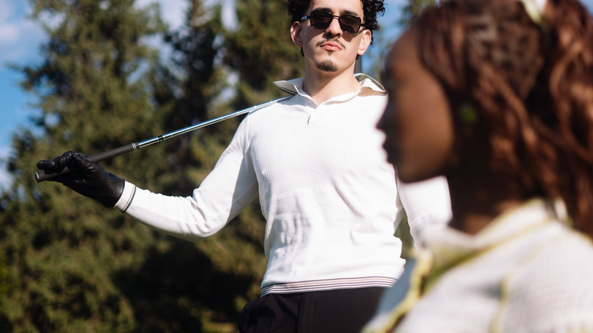 Man in sunglasses holding a golf club on a course